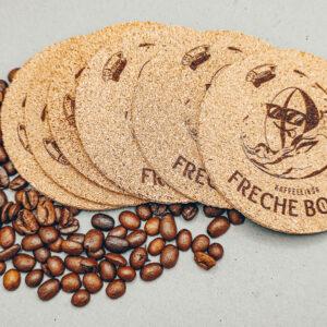 Sechs Untersetzer liegen nebeneinander. Kaffeebohnen als Deko.