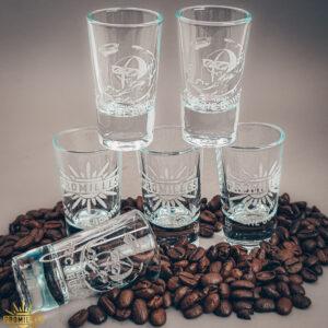 Sechs mit einem Laser graviert 2 cl Schnapsgläser. Fünf sind gestapelt und eins liegt waagerecht. Deko drum herum ist aus Kaffeebohnen.